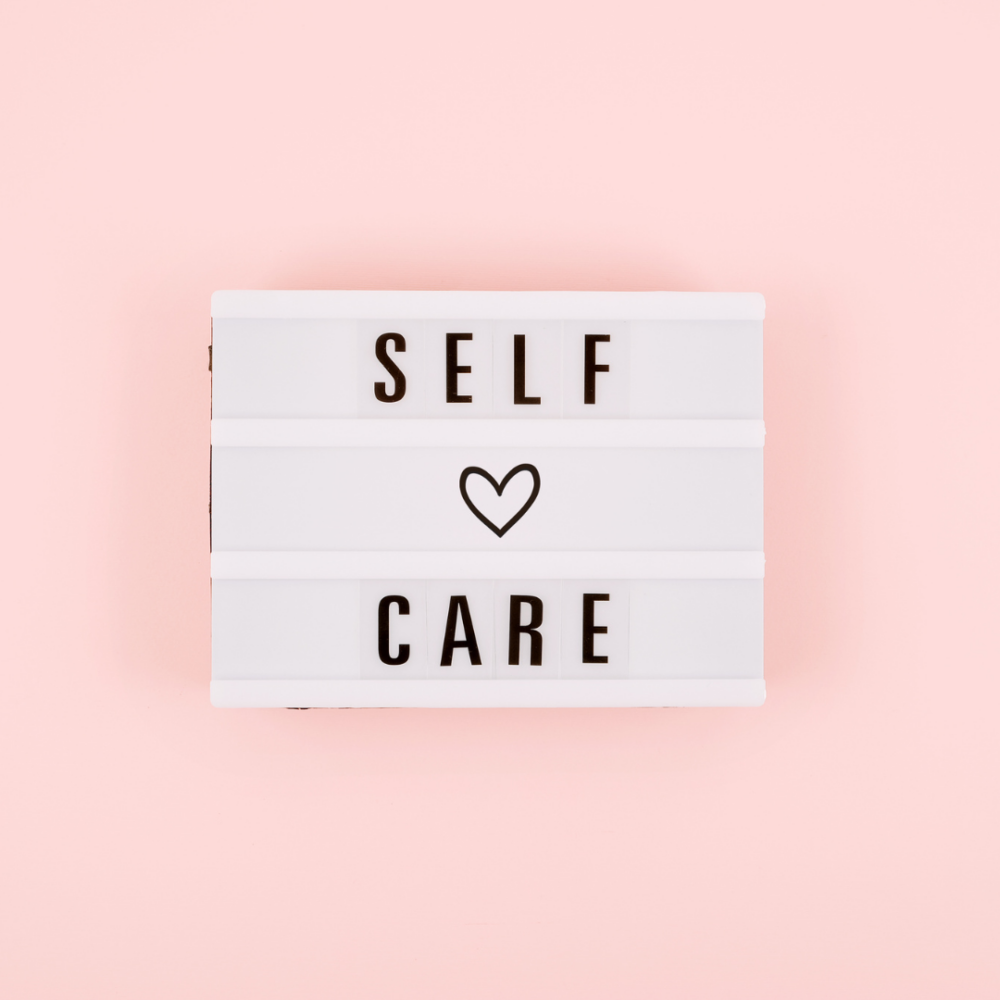 A light board with "Self-Care" spelled out with a heart in the middle.